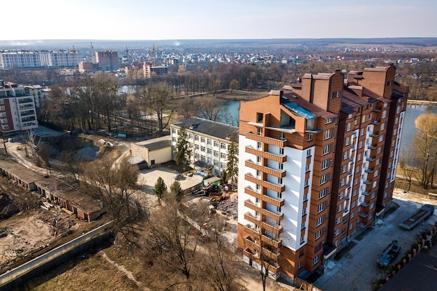 Aerial view of new tall apartment building in quiet area on developing city landscape under bright blue sky.