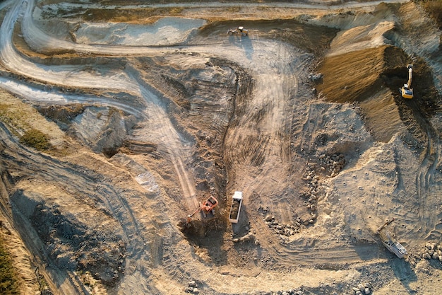 Photo aerial view of open pit mine of sandstone materials for construction industry with excavators and dump trucks. heavy equipment in mining and production of useful minerals concept