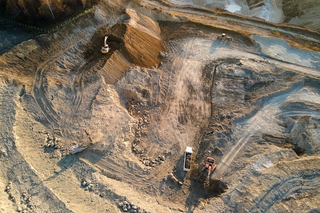 Aerial view of open pit mining site of limestone materials for construction industry with excavators and dump trucks.