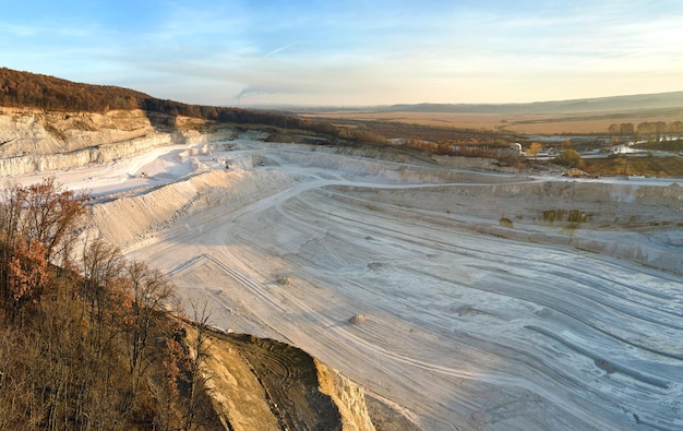 Aerial view of open pit mining site of limestone materials for construction industry with excavators and dump trucks