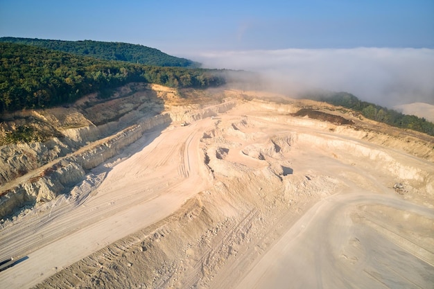 Aerial view of open pit mining site of limestone materials extraction for construction industry with excavators and dump trucks