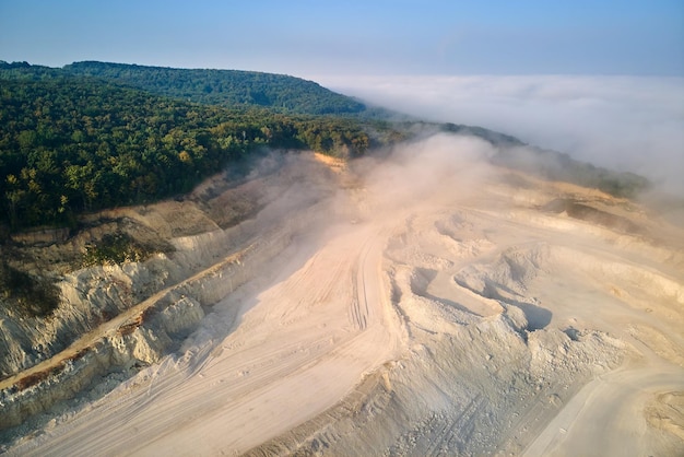 Aerial view of open pit mining site of limestone materials extraction for construction industry with excavators and dump trucks