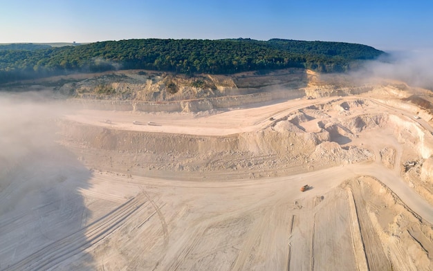 Aerial view of open pit mining site of limestone materials extraction for construction industry with excavators and dump trucks