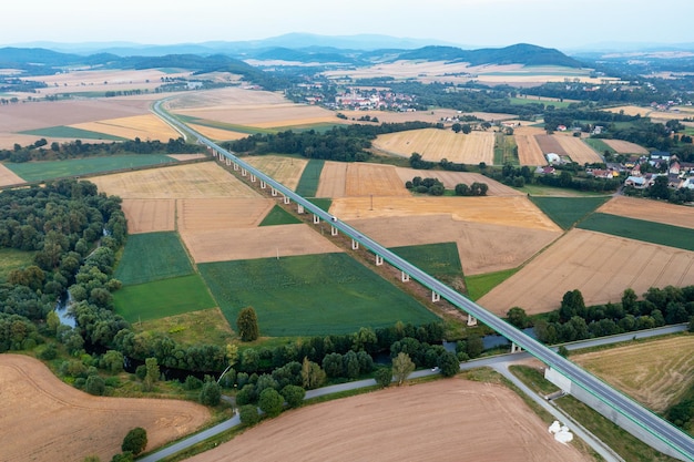 Aerial view of overpass surrounded by green fields long bridge