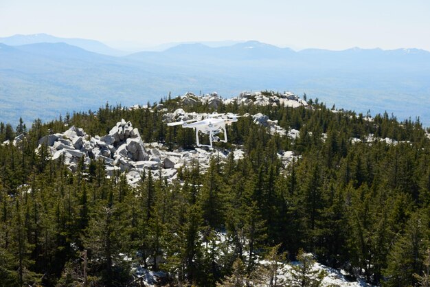 Aerial view quadrocopter with camera flying over rocky mountain covered with wild conifer woods nati