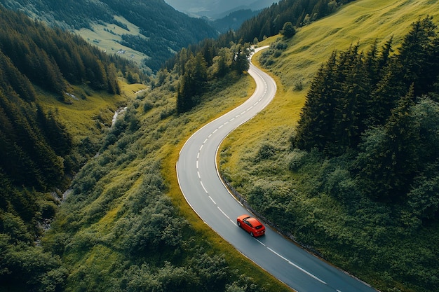 Aerial view of red car driving on scenic winding road through lush green mountains