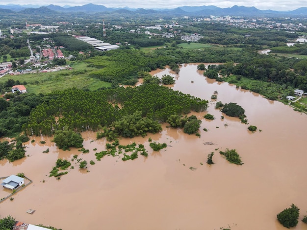 Aerial view river flood village countryside Asia and forest tree Top view river with water flood from above Raging river running down jungles lake flowing wild water after the rain