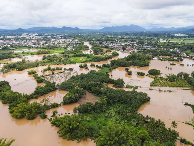 Aerial view river flood village countryside Asia and forest tree Top view river with water flood from above Raging river running down jungles lake flowing wild water after the rain