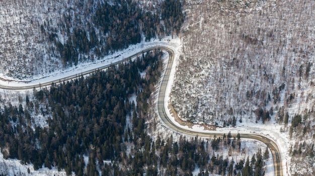 Aerial view of the river and taiga forests and road in the winter  springtime  abstract landscape of northern nature with drone