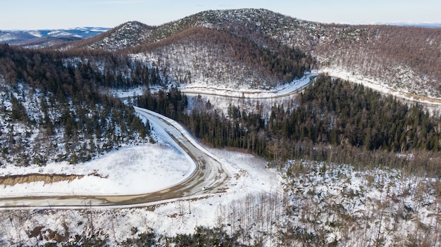 Aerial view of the river and taiga forests and road in the winter  springtime  abstract landscape of northern nature with drone