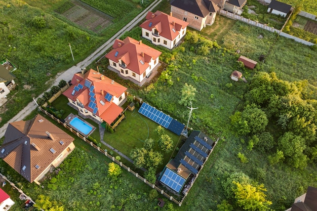 Aerial view of rural residential area with private homes between green fields at sunrise.