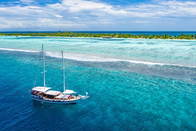 Aerial view of sailing boat anchoring on coral reef. Drone view, water sport theme. Luxury cruise