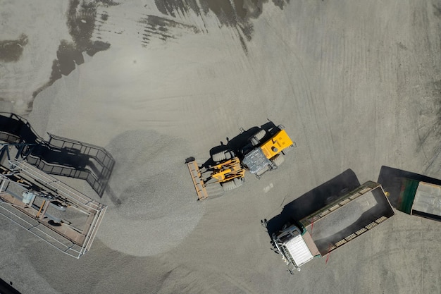 Aerial view of sand loaders are shoveling rocks into dump trucks