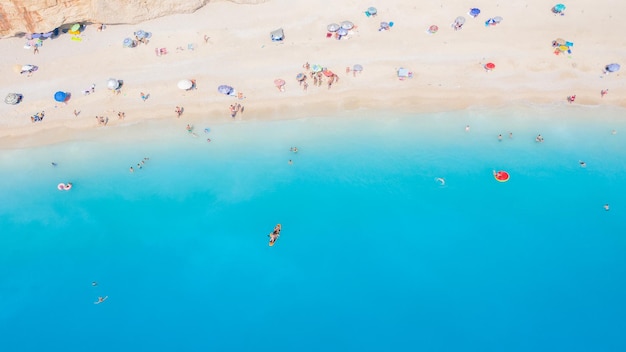 Aerial view of sandy beach with colorful umbrellas swimming people in sea bay with transparent blue water at sunny day in summer Travel in Mallorca Balearic islands Spain Top view Seascape