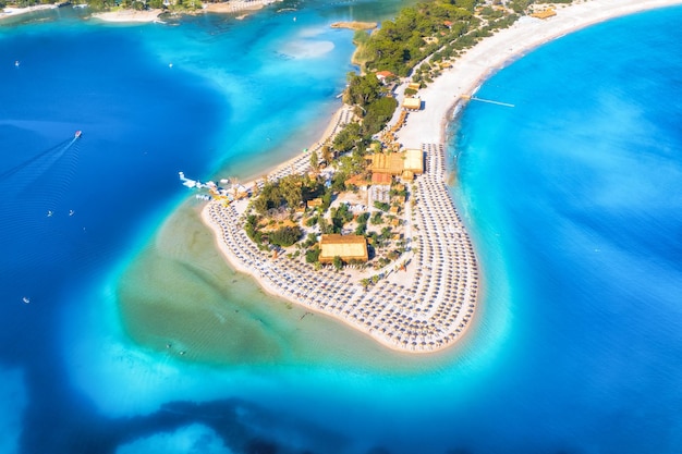 Aerial view of sandy beach with umbrellas green forest at sunny day in summer Blue lagoon in Oludeniz Turkey Tropical landscape with sea bay island white sandy bank blue water Top view Nature