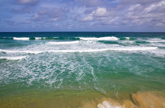 Aerial view of sea crashing waves White foaming waves on beach sand Top view beach seascape view Nature sea ocean background