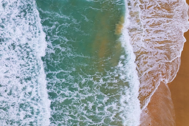 Aerial view of sea crashing waves White foaming waves on beach sand Top view beach seascape view Nature sea ocean background