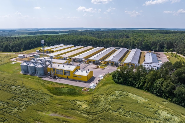 Aerial view on silos and agroindustrial livestock complex on agroprocessing and manufacturing plant with modern granary elevator chicken farm rows of chicken coop