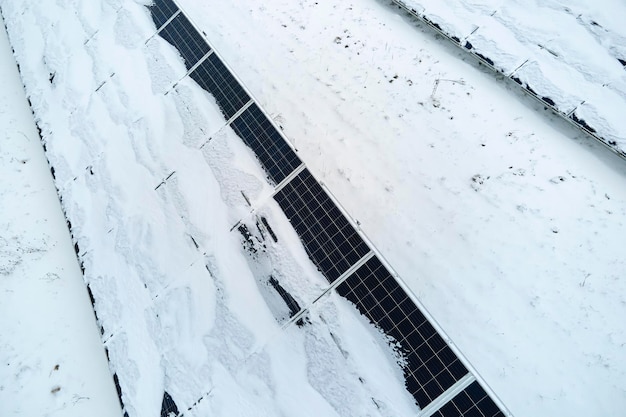 Aerial view of snow melting from covered solar photovoltaic panels at sustainable electric power plant for producing clean electrical energy Low effectivity of renewable electricity in winter