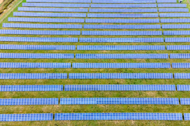 Aerial view of solar power plant on green field. Electric farm with panels for producing clean ecologic energy.