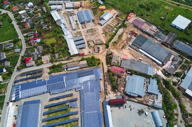 Aerial view of solar power plant with blue photovoltaic panels mounted on industrial building roof for producing green ecological electricity. Production of sustainable energy concept.