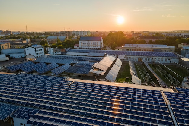 Aerial view of solar power plant with blue photovoltaic panels mounted on industrial building roof for producing green ecological electricity Production of sustainable energy concept