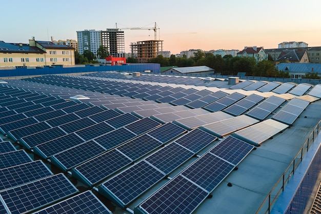 Aerial view of solar power plant with blue photovoltaic panels mounted on industrial building roof for producing green ecological electricity Production of sustainable energy concept