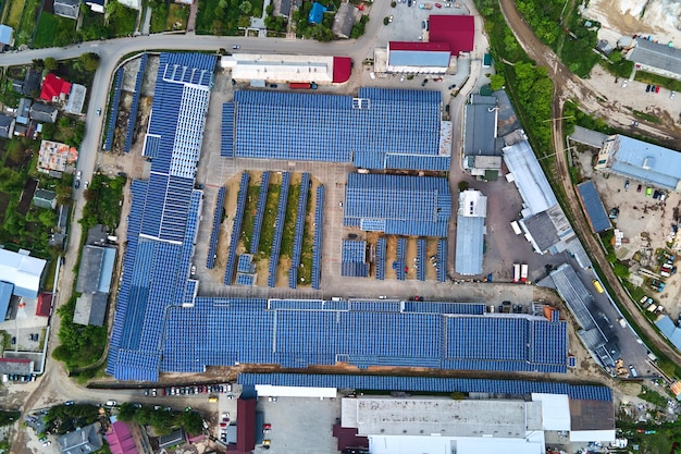 Aerial view of solar power plant with blue photovoltaic panels mounted on industrial building roof for producing green ecological electricity Production of sustainable energy concept