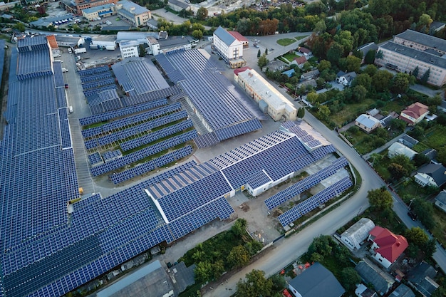 Aerial view of solar power plant with blue photovoltaic panels mounted on industrial building roof for producing green ecological electricity Production of sustainable energy concept