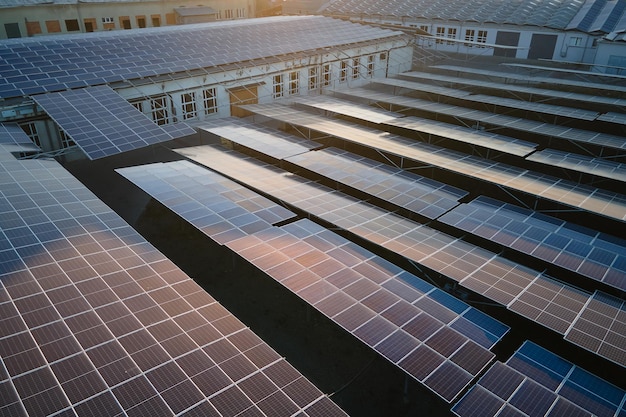 Aerial view of solar power plant with blue photovoltaic panels mounted on industrial building roof for producing green ecological electricity Production of sustainable energy concept