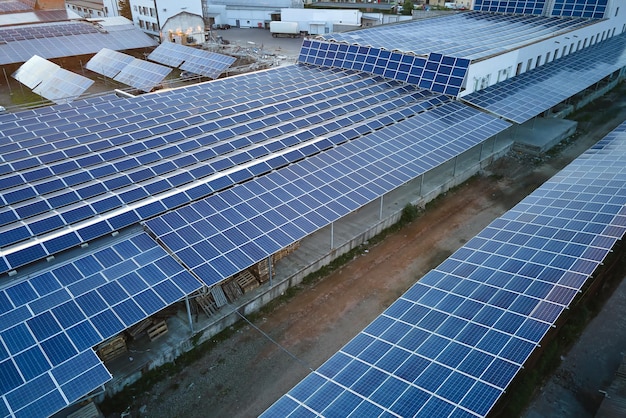 Aerial view of solar power plant with blue photovoltaic panels mounted on industrial building roof for producing green ecological electricity Production of sustainable energy concept