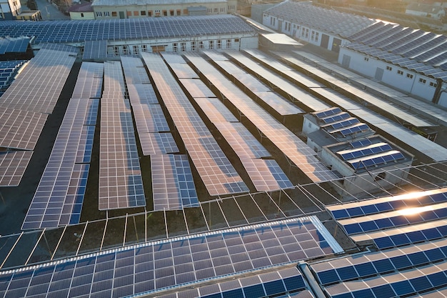 Aerial view of solar power plant with blue photovoltaic panels mounted on industrial building roof for producing green ecological electricity Production of sustainable energy concept