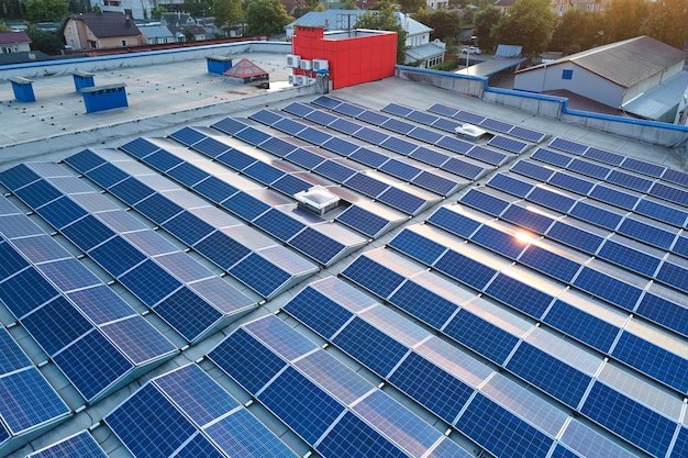 Aerial view of solar power plant with blue photovoltaic panels mounted on industrial building roof for producing green ecological electricity Production of sustainable energy concept