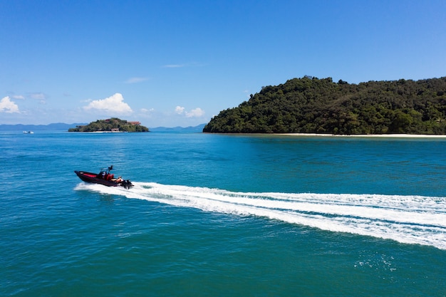 Aerial view of a speedboat traveling over blue sea leaving a trail of white waves and bubbles behind with copyspace