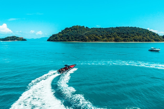 Aerial view of a speedboat traveling over blue sea leaving a trail of white waves and bubbles behind