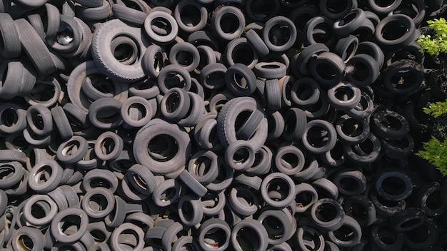 Aerial view of the stark contrast between a massive landfill of used car tires and the surrounding green trees Tire dump showcases human waste impact on environment