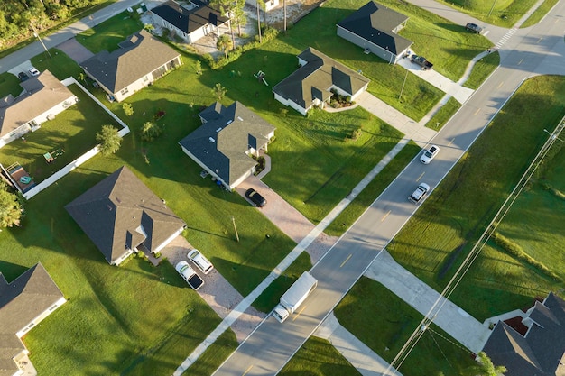 Aerial view of street traffic with driving cars in small town American suburban landscape with private homes between green palm trees in Florida quiet residential area