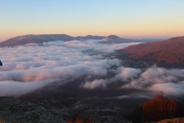 Aerial view of sunrise in the mountains Valley in clouds with pink reflexes from sun