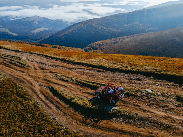 Aerial view of suv off road travel climbing up by mountain hill copy space autumn season above the clouds