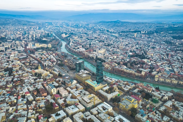 Aerial view of Tbilisi city center with churches and modern buildings and emerald waters of Kura river