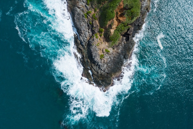 Aerial view Top down seashore big wave crashing on rock cliff Beautiful dark sea surface in sunny day summer background Amazing seascape top view seacoast at Phuket Thailand.