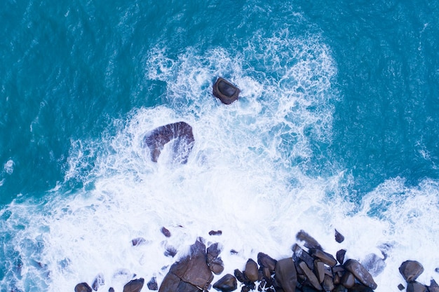 Aerial view Top down seashore big wave crashing on rock cliff Beautiful dark sea surface in sunny day summer background Amazing seascape top view seacoast at Phuket Thailand