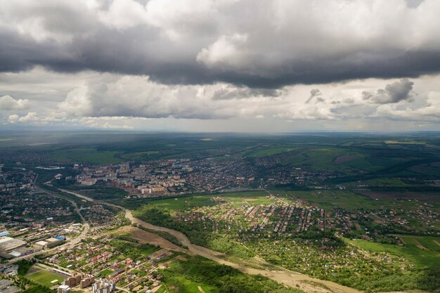 Aerial view of town or village with rows of buildings and streets between green fields in summer.