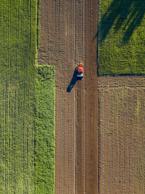 Aerial view of tractor on the agricultural field sowing. Tractors working on the agricultural field in spring. Photo by drone