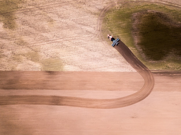 Aerial view of the tractor in the field, agricultural field work. Tractor cultivating field, aerial view