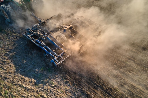 Aerial view of tractor plowing agriculural farm field preparing soil for seeding in summer