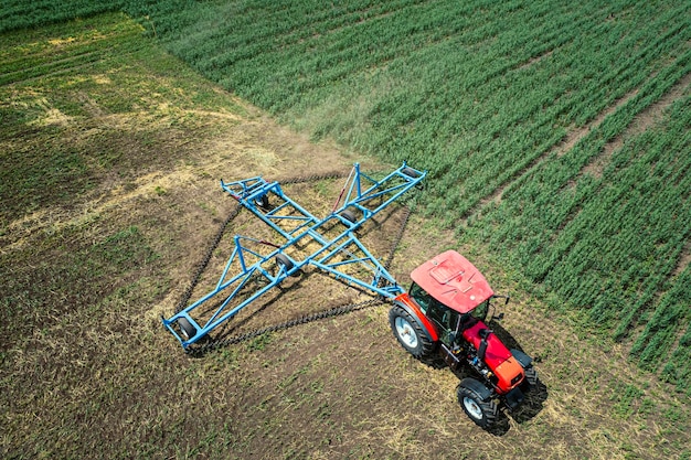 Aerial view of tractor spraying the chemicals on the large green field