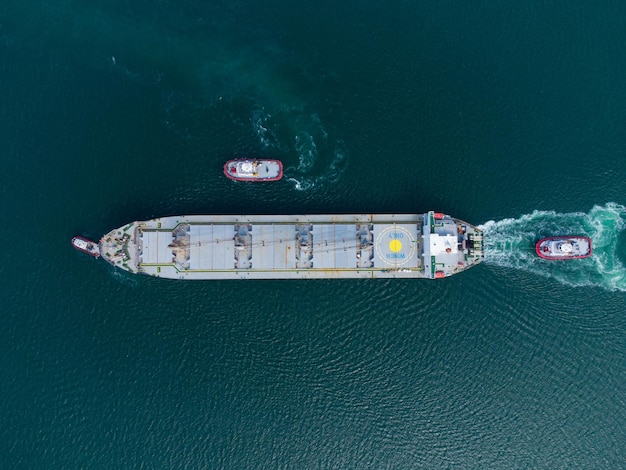 Aerial view of tug boat assisting big bulk carrier cargo ship Large ship escorted by tugboat