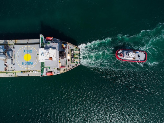 Aerial view of tug boat assisting big bulk carrier cargo ship Large ship escorted by tugboat