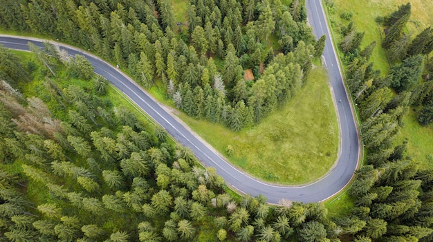 Aerial view of twisting road among the forest and trees. Sunset field in Lithuania.